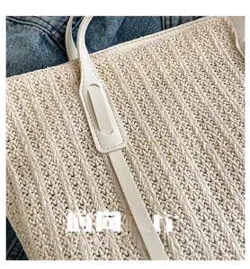 Close-up of beige woven tote bag with white leather straps and fine stitching detail
