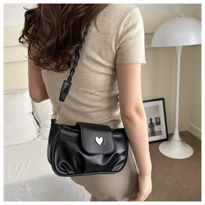 Detail of black pleated shoulder bag with silver heart buckle and braided strap