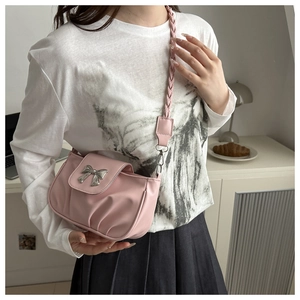 Détail du sac à bandoulière rose plissé avec nœud en métal argenté et sangle tissée