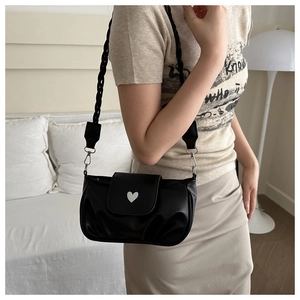 Detail view of black pleated underarm bag with white heart logo and woven strap