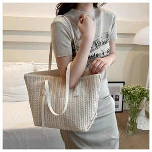 Detail shot of straw woven tote bag texture with slim white shoulder straps for summer