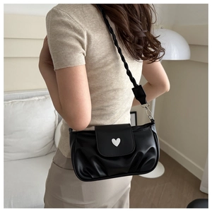 Detail of black pleated crossbody bag with white heart buckle and braided shoulder strap