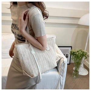 Detail of hand-woven cream tote bag showing striped fiber texture and white leather straps