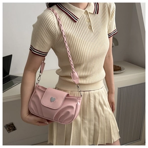 Detail of pink pleated handbag featuring a heart buckle and braided shoulder strap