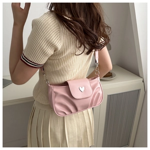 Close-up of pink pleated shoulder bag featuring a silver heart-shaped metal buckle detail