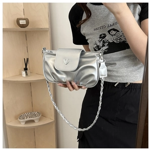 Detail of silver pleated bag with heart ornament and braided twist shoulder strap