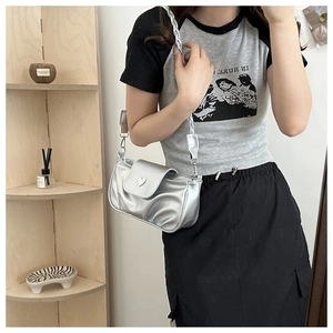 Detail of silver pleated shoulder bag with heart buckle and braided strap on model