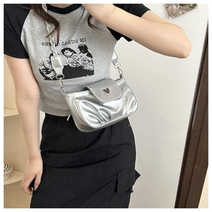 Mirror selfie showing silver pleated crossbody bag with heart buckle and woven strap