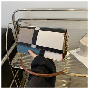 Detailed close-up of a geometric patchwork shoulder bag with gold chain and leather strap