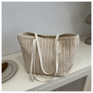 Detail of woven straw tote bag texture with elegant white leather handles for summer