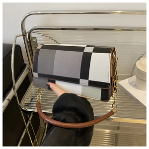 Detail of checkered crossbody bag featuring a round brown top handle and gold chain strap