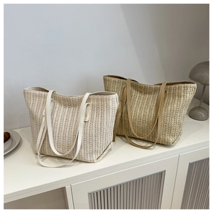 Detail of woven straw tote bags in beige and khaki with vertical pleated textures