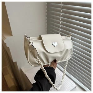 Detail of white pleated handbag with silver heart buckle and woven braided strap