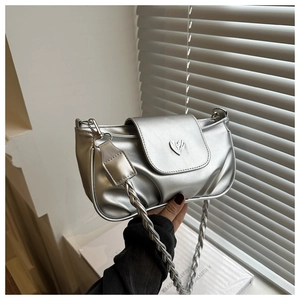 Detailed view of silver metallic bag with heart buckle and woven chain strap