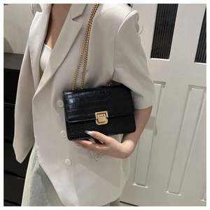 Détail du sac en cuir noir motif crocodile avec chaîne dorée et fermoir en métal chic