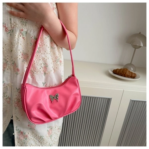 Detail of pink shoulder bag featuring silver butterfly emblem and pleated texture finish