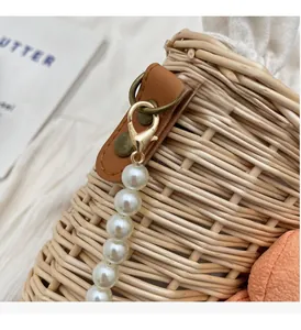 Close-up of woven straw bag with faux pearls and light gold hardware accents