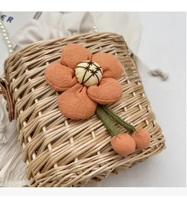 Detail of woven straw basket bag with a large orange floral decor and pearl chain strap