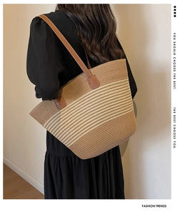 Contrast woven straw tote bag with brown leather handles worn over shoulder by a model