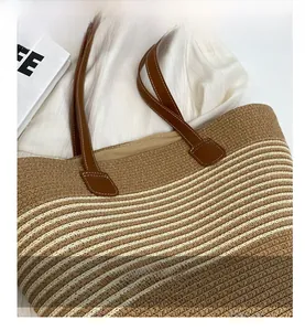 Close-up of woven straw texture with cream stripes and brown leather strap detailing