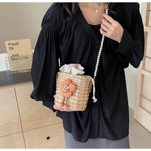 Handwoven straw bucket bag with orange flowers and a pearl strap for beach vacations