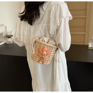 Detail of woven straw bucket bag with floral accents and white pearl chain strap