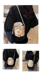 Detail of hand-woven straw bucket bag with floral accents and a pearl chain strap