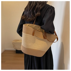 Detail of hand-woven tote bag showing texture, brown leather straps, and striped pattern