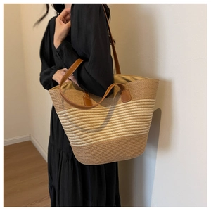 Detail of hand-woven straw tote with brown leather handles and chic contrast stitching