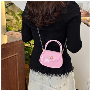 Close-up of pink glossy PVC mini bag with pearl buckle and silver metal chain strap