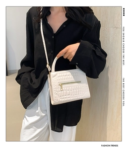 Detail view of cream white textured leather handbag with gold zipper and shoulder strap