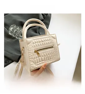 Close-up of cream crocodile pattern bag with gold zipper and detachable strap details