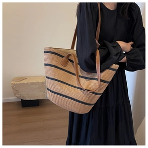 Detail of hand-woven straw tote with navy blue stripes and premium leather shoulder strap