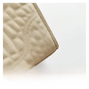 Macro detail of beige pebble-textured leather with precise stitching on high-quality bag