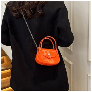 Mini orange PVC jelly bag with pearl buckle and metal chain strap shown on a model