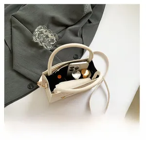 Top-down view of cream quilted handbag interior showing space for smartphone and lipstick