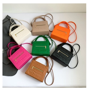Flat lay of small crocodile pattern crossbody bags in seven colors with gold hardware