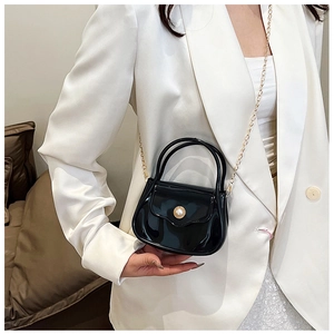 Close-up of black glossy PVC mini bag with gold floral pearl clasp and chain strap