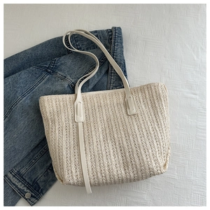 Close-up of beige woven tote bag texture with elegant white faux leather strap