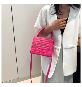 Detail showing the crocodile texture and zipper of the rose red crossbody handbag