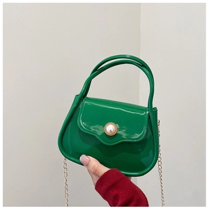 Close-up of green mini PVC bag with pearl buckle and golden chain strap