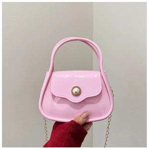 Close-up of pink PVC mini bag featuring a large pearl clasp and gold chain strap