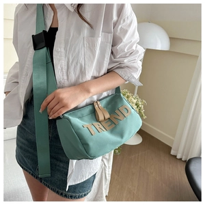Detail of mint green cylindrical bag featuring TREND letter applique and wide strap