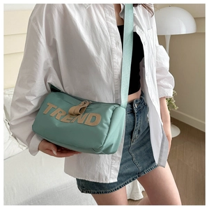 Detail of mint green crossbody bag featuring TREND patch with stylish wide shoulder strap