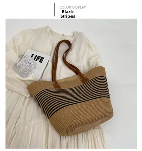 Detail of hand-woven straw tote with black stripes and brown leather handles