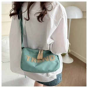 Detail of mint green crossbody bag with TREND letter patch and adjustable nylon strap