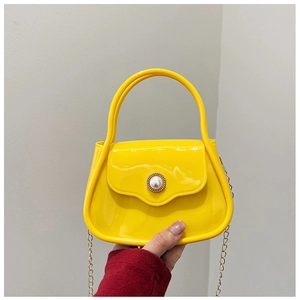 Detail of yellow PVC mini bag with large pearl buckle and golden chain strap