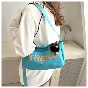 Detail of blue nylon crossbody bag with TREND letter patch and black plush monster charm