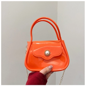 Detail of bright orange jelly bag with white pearl decor and golden metal chain