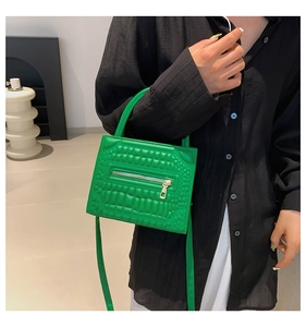 Detail of bright green faux crocodile pattern handbag worn with casual outfit